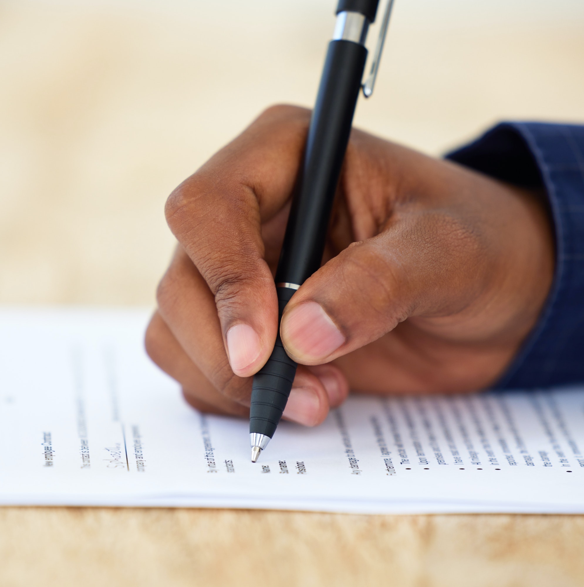 Shot of an unrecognisable businessman filling in a form on a desk in an office